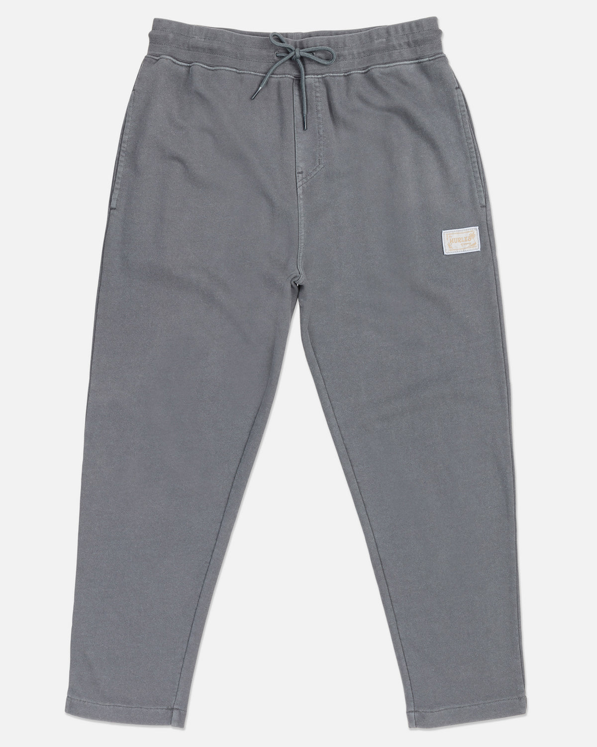A pair of gray joggers with elastic waistband and straight hem, featuring side pockets and a small brand patch on the left leg.