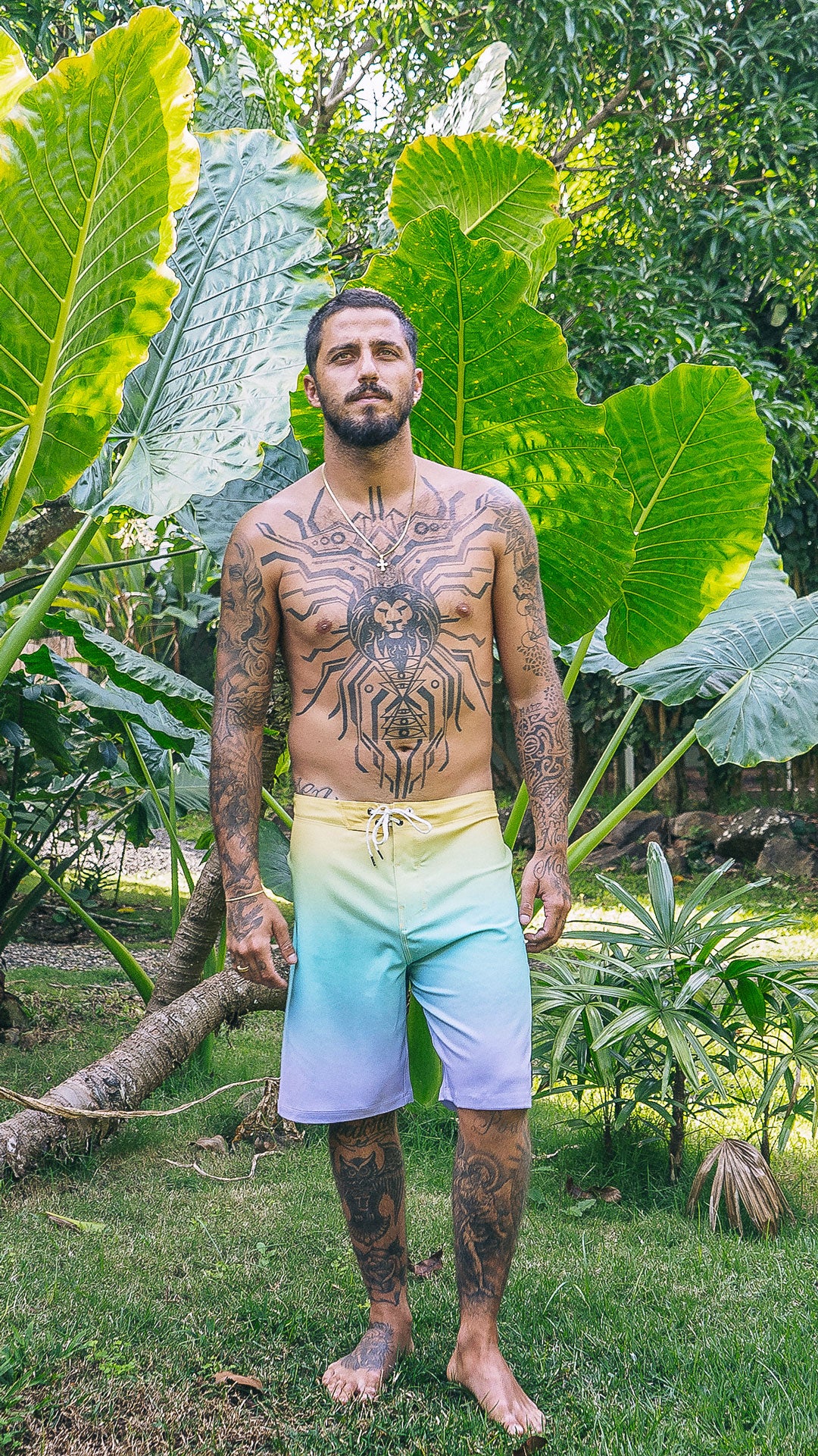 Man with tattoos standing in a lush green garden