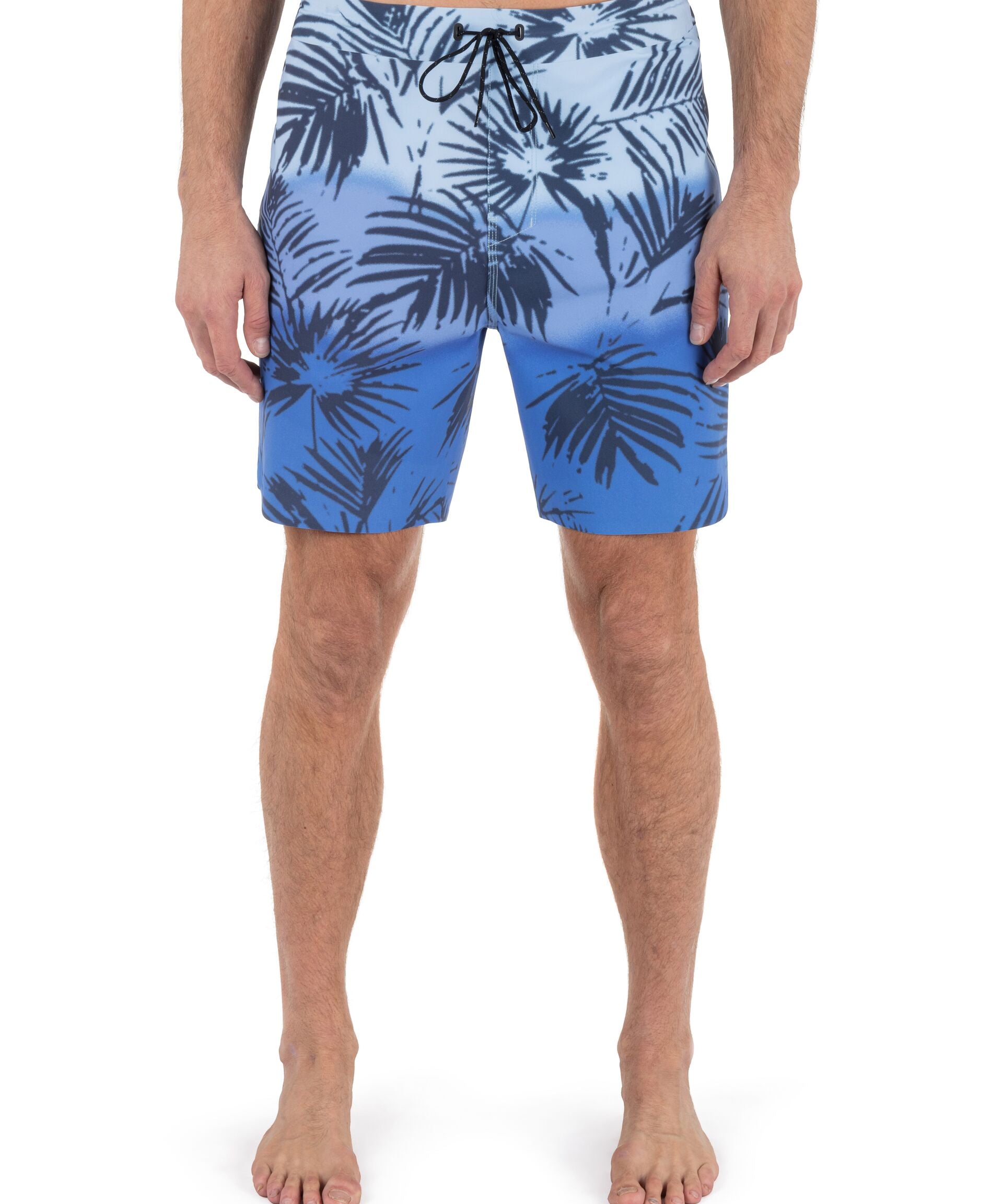 Blue leaf-patterned swim shorts worn by a person on a white background