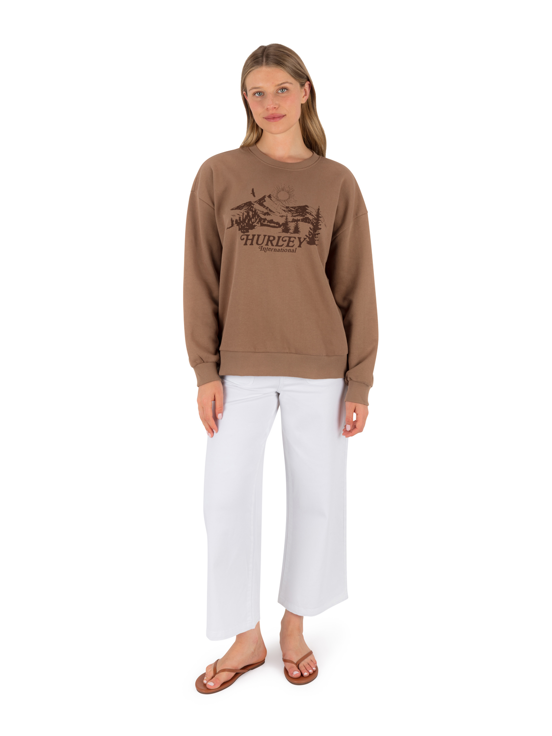 Woman wearing a brown sweatshirt with a logo and text, standing against a white background