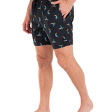 Person wearing black shorts with colorful bird pattern on a white background