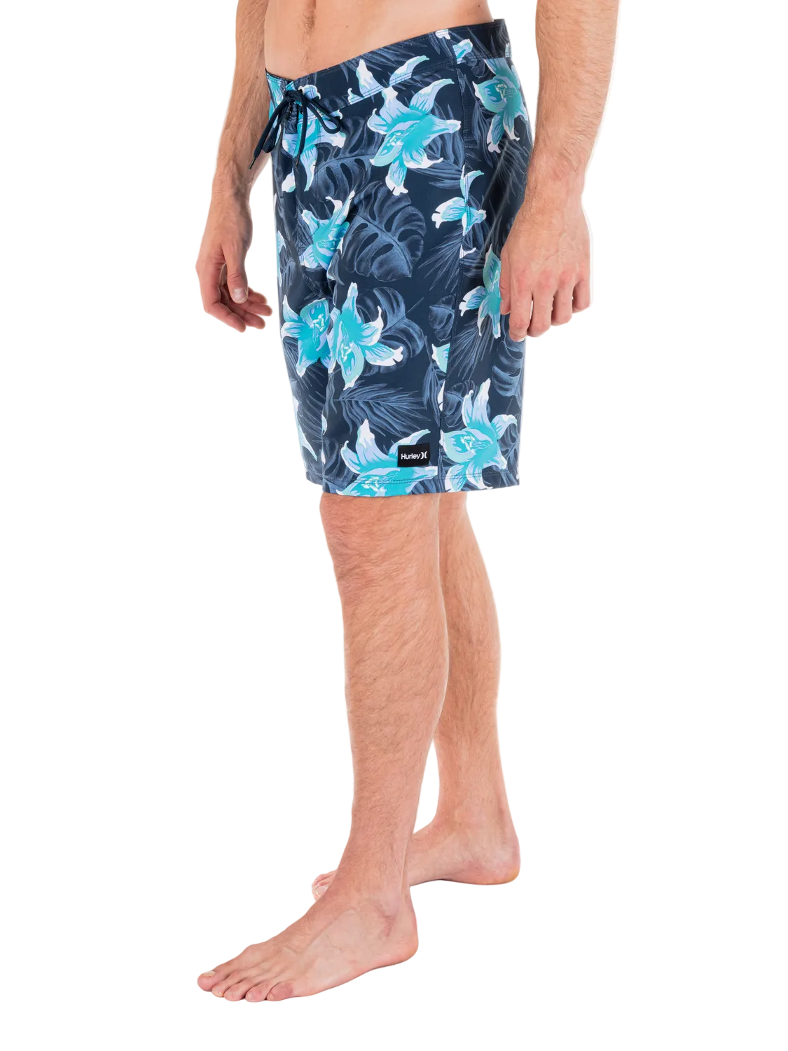 Person wearing navy floral swim shorts on a white background